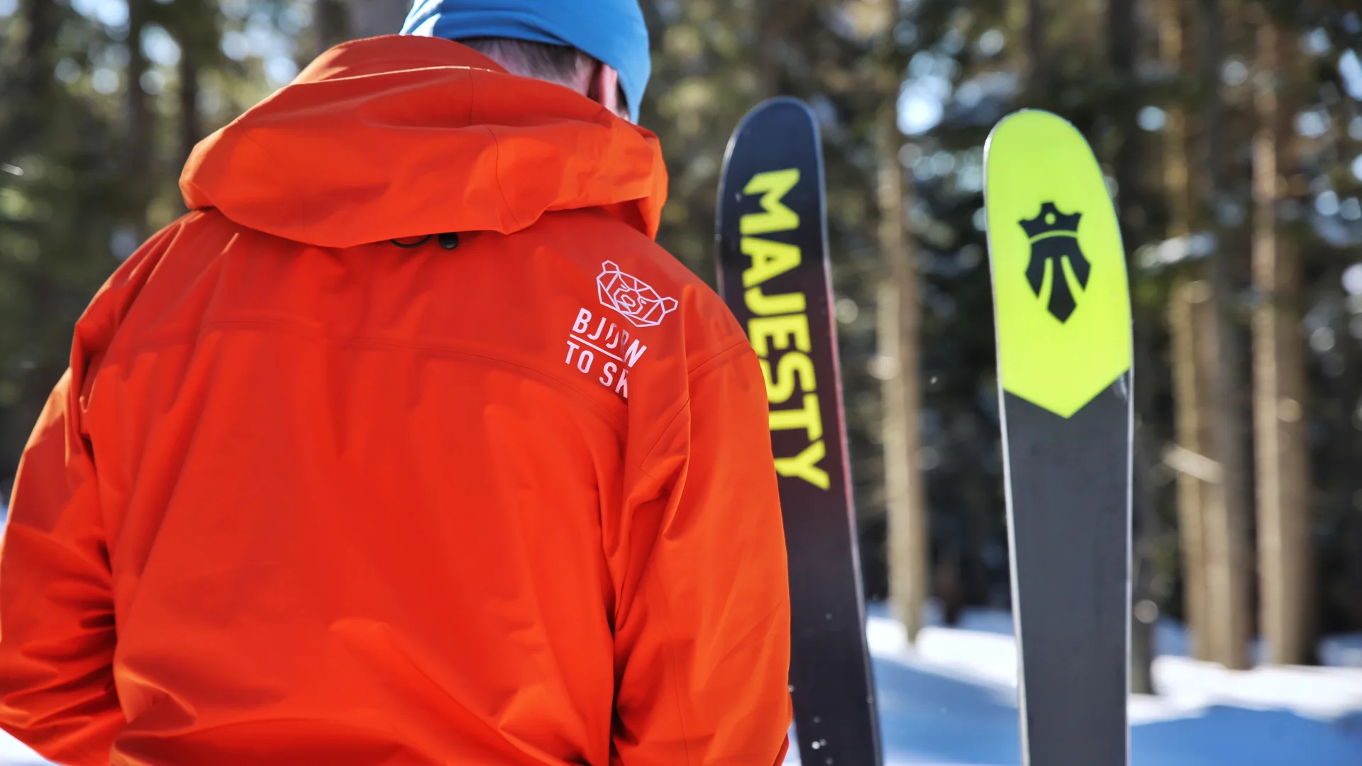 Osoba w kurtce BJØRN Ski stojąca obok nart w zimowym lesie