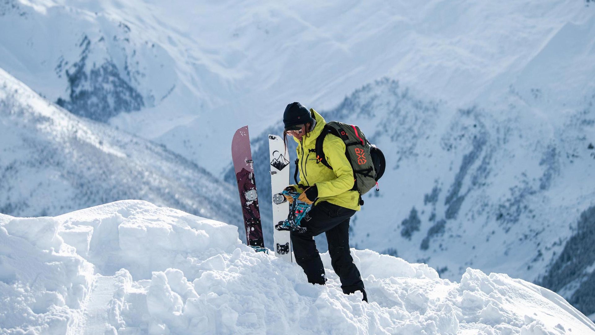 Splitboarder przygotowuje rozdzieloną deskę do podejścia na śnieżnej grani.